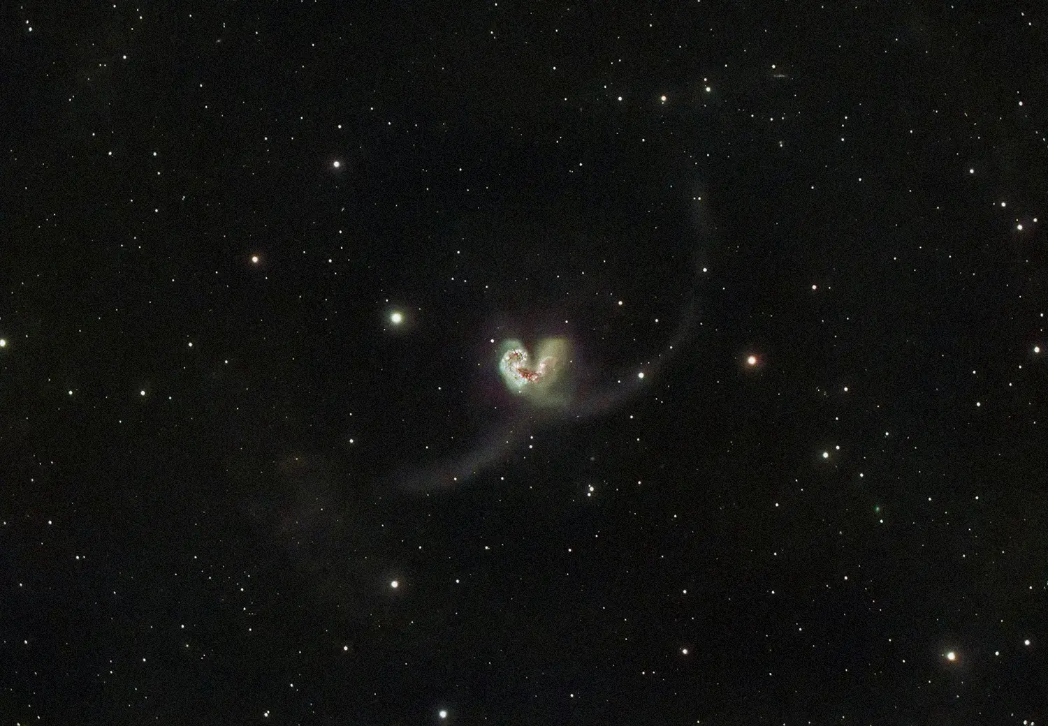 Photo of a star-filled space with a dark black sky, showcasing a small galaxy at the center where stars cluster together to form a delicate, elegant heart shape.