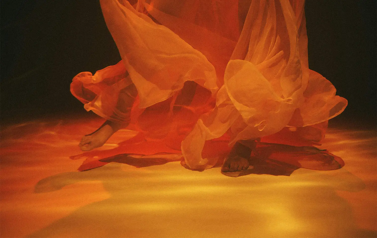 A woman's legs and flowing dress captured mid-dance in a natural outdoor setting, symbolizing freedom and self-expression.