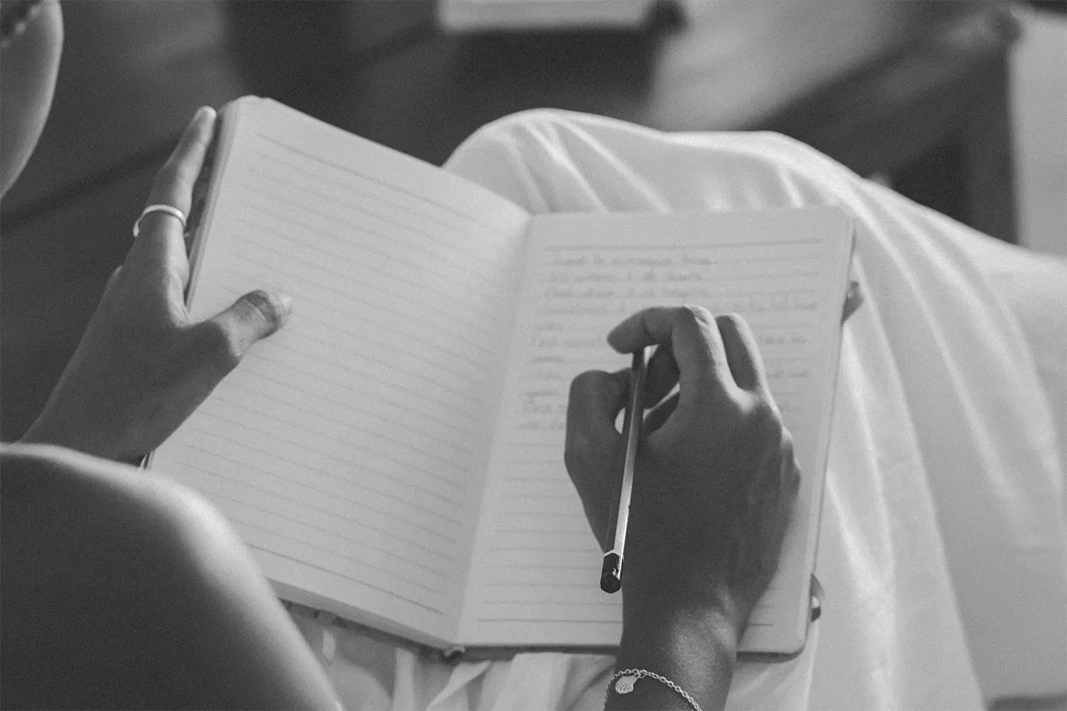 A woman's hands writing in a notebook with a cup of coffee nearby, representing journaling for love manifestation and mindfulness.